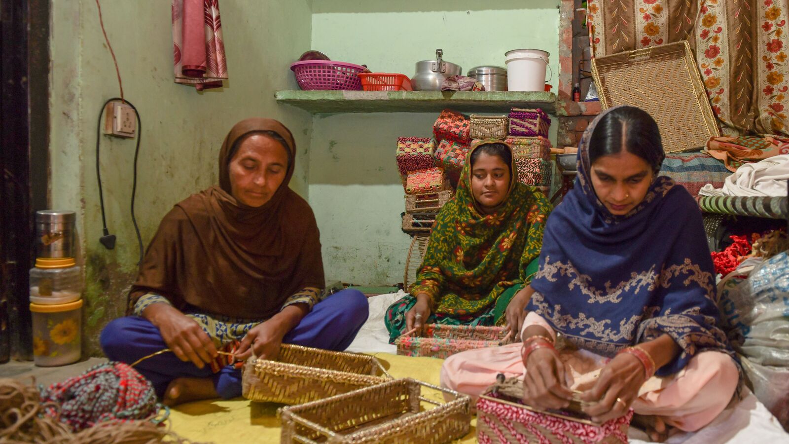 Three women weaving baskets together