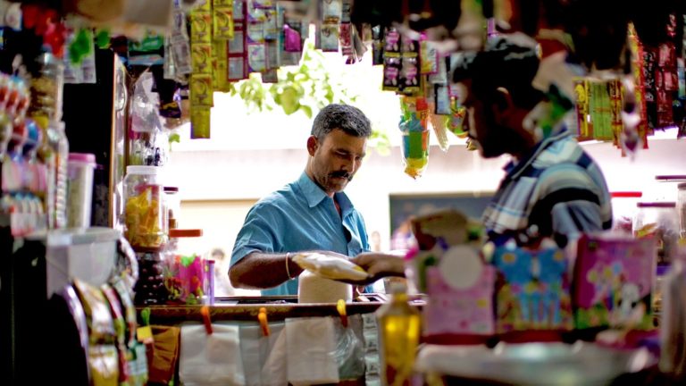 Shop owner surrounded by merchandise.