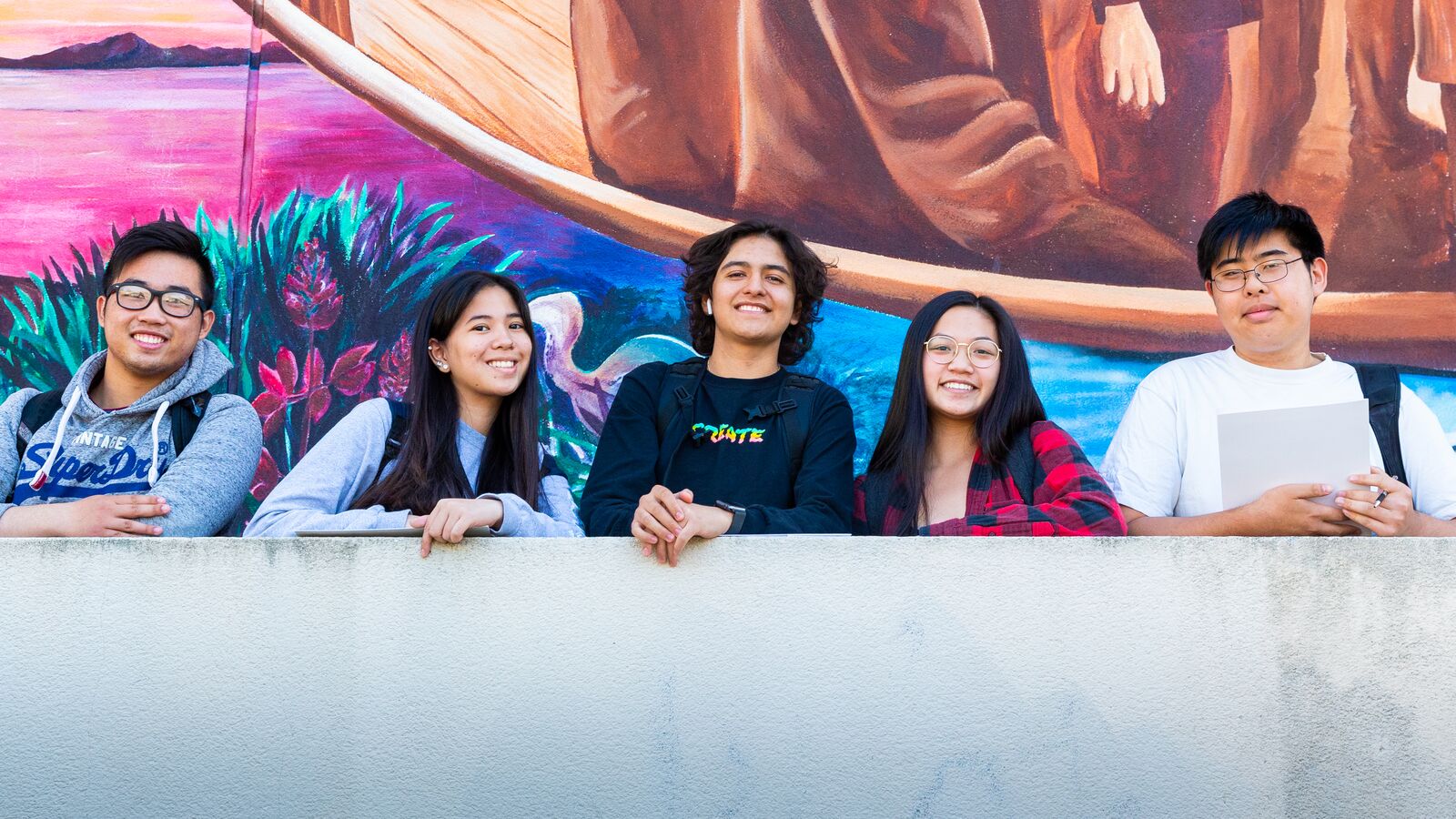 10,000 Degrees students smiling together in front of a Mural