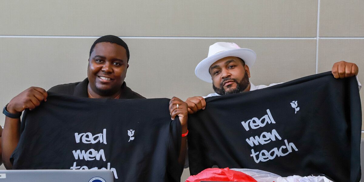 Fellowship for Black and Latino Male Educators Fellows smiling at camera holding Real Men Teach tshirts