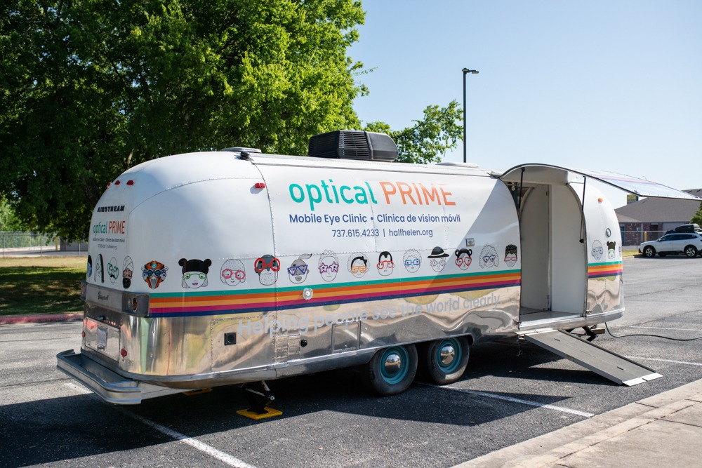Photo of optical Prime 2 parked outside of a school. This is the newly refurbished vintage airstream and mobile clinic for half Helen. 