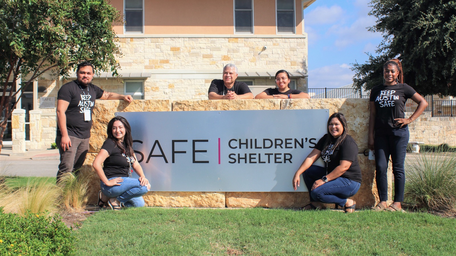 SAFE Alliance Childrens Shelter exterior signage, surronded by SAFE Alliance staff.