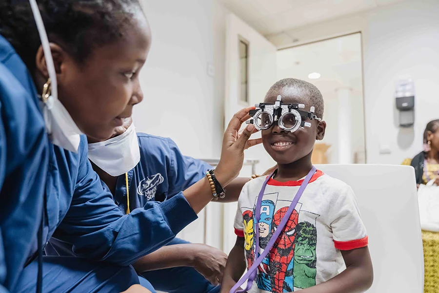 Mercy Ships staff help a young boy with his eye exam.