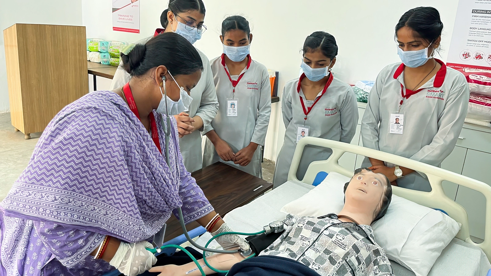 An instructor demonstrates blood pressure measurement to a group of Indian students.