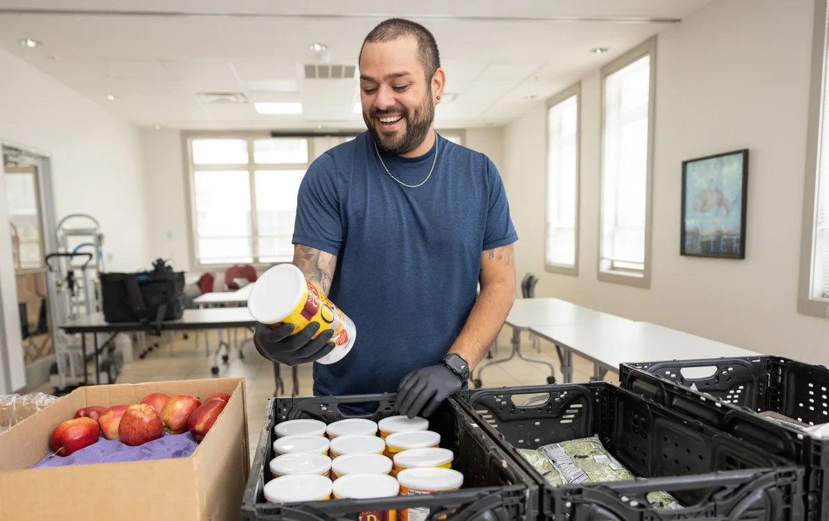 A man inspects crates of food in a food pantry.