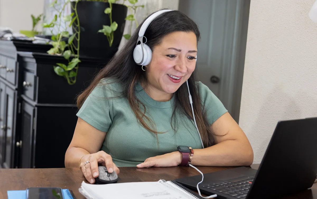 A Community Health Worker wears a headset to take a virtual call at her computer.