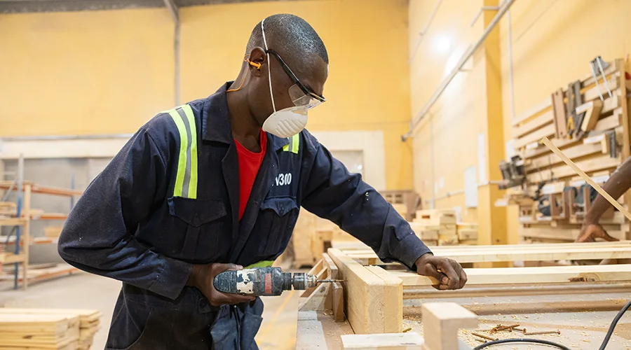 A Moko employee drills into wood in a workshop.