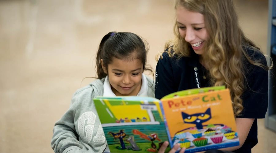 A Literacy First tutor reads a book with a student.