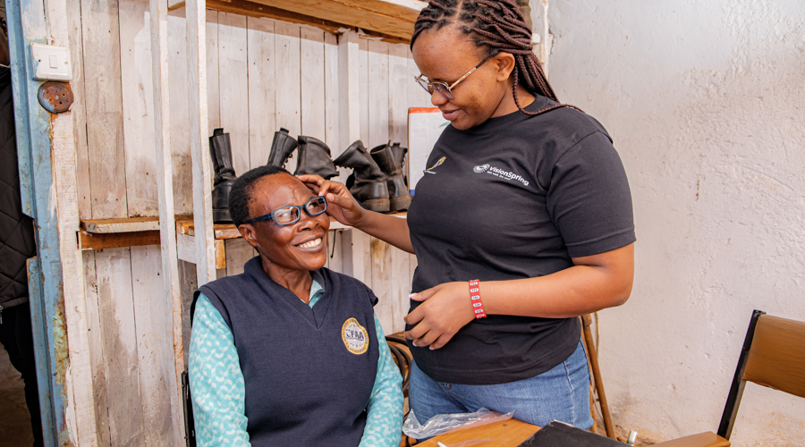 A VisionSpring staff person helps a woman try on her new glasses.