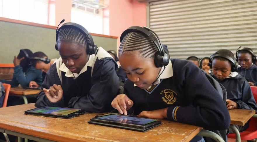 Two students work on tablets in a classroom.