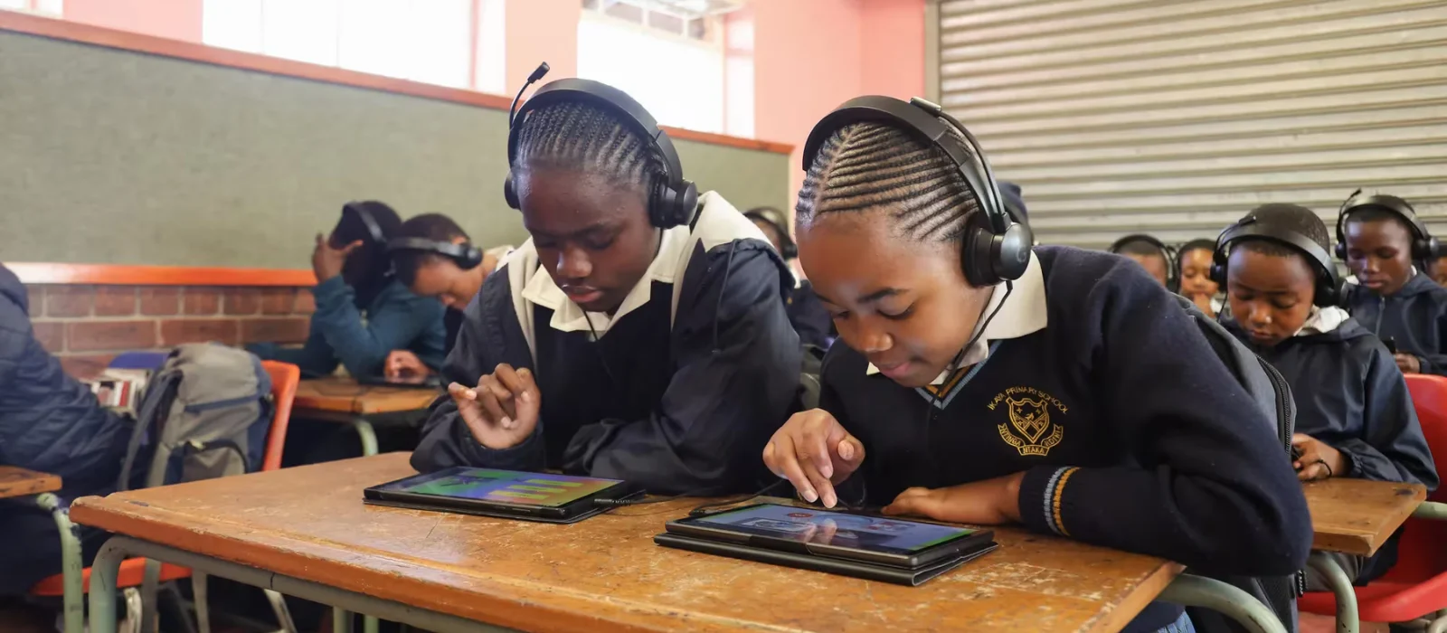 Two students work on tablets in a classroom.