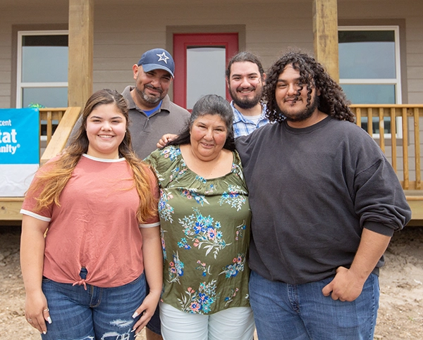 A family stands in front of their newly built home.