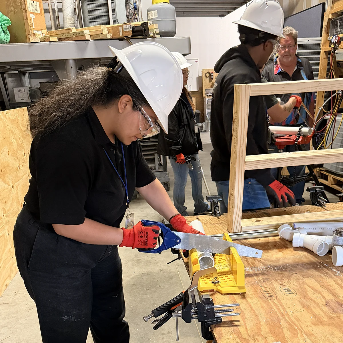 A young woman uses a saw during training.
