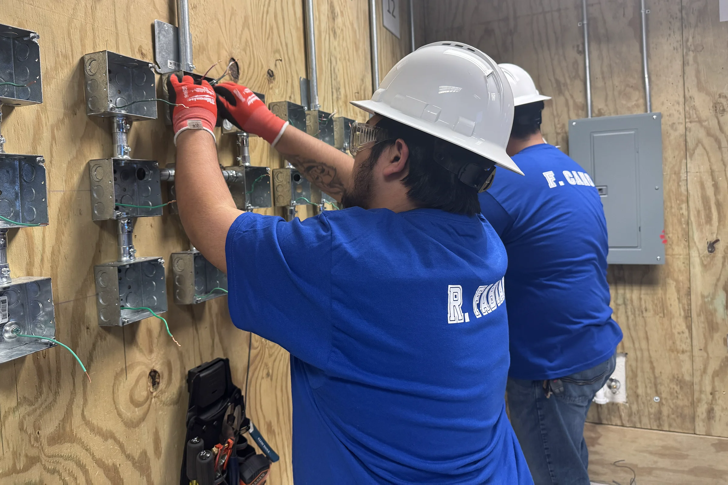 Two young men perform electrical work.